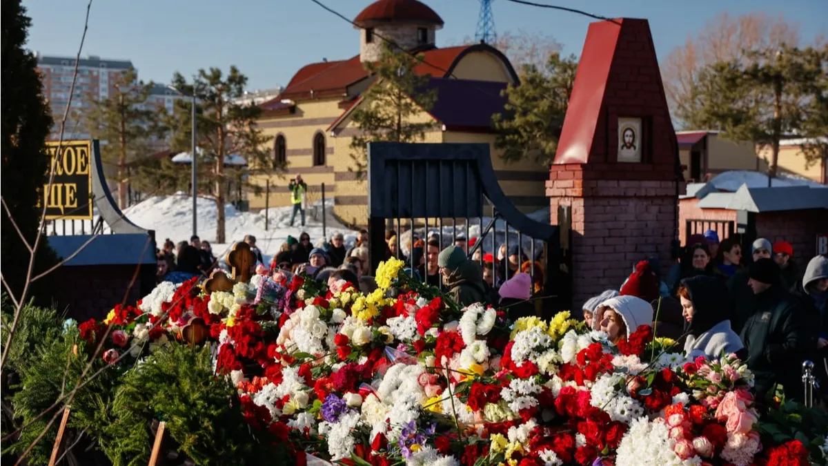На третий день после похорон Алексея Навального* на могиле видна лишь верхушка креста – люди приносят цветы на Борисовское кладбище 